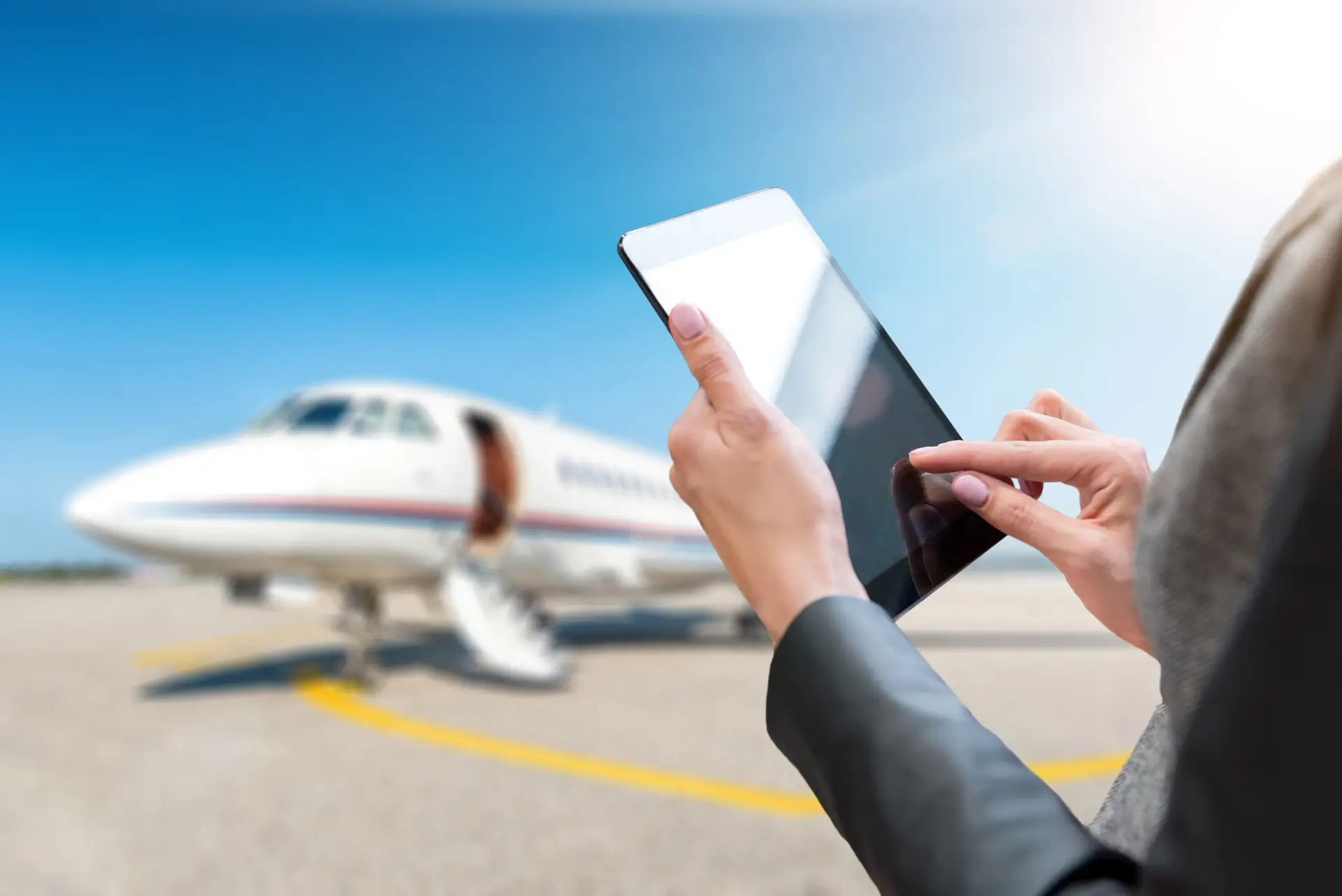 Hands using a tablet beside a parked business jet