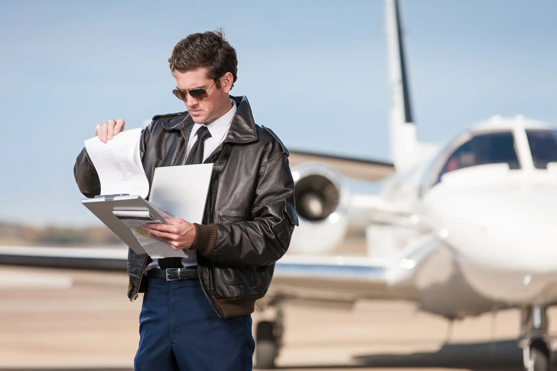 Pilot reviewing papers beside a parked business jet